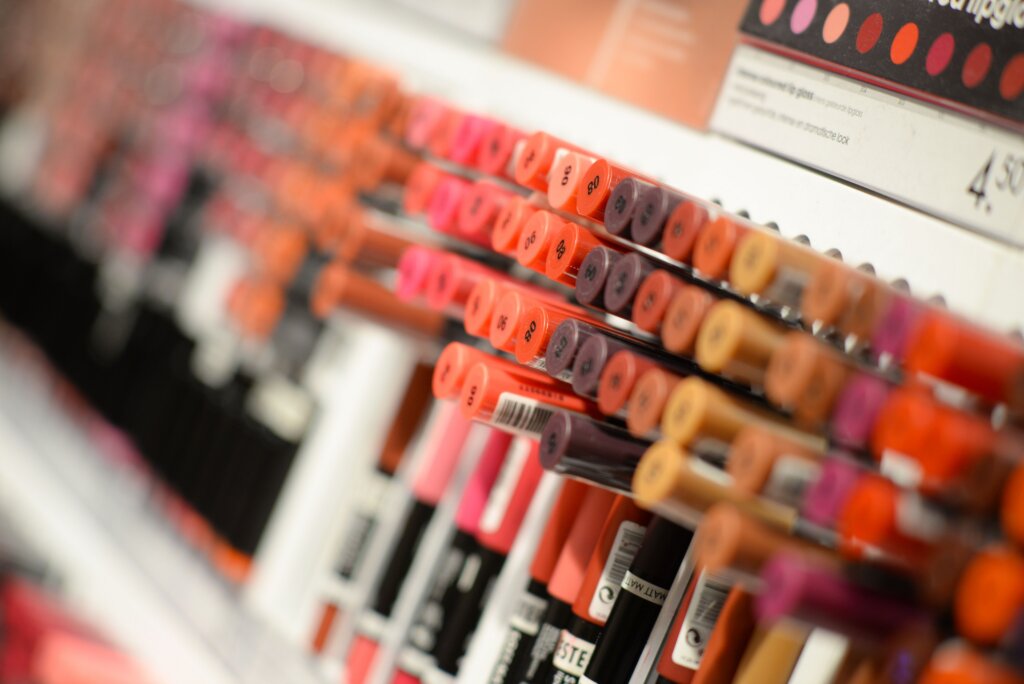 Close-up of a lipstick display shelf with rows of colorful shades at a beauty store.