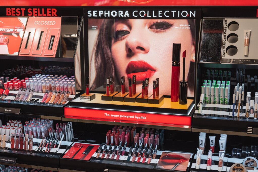 Sephora Collection display featuring lip products, mascaras and other cosmetics arranged beneath a large promotional beauty image.