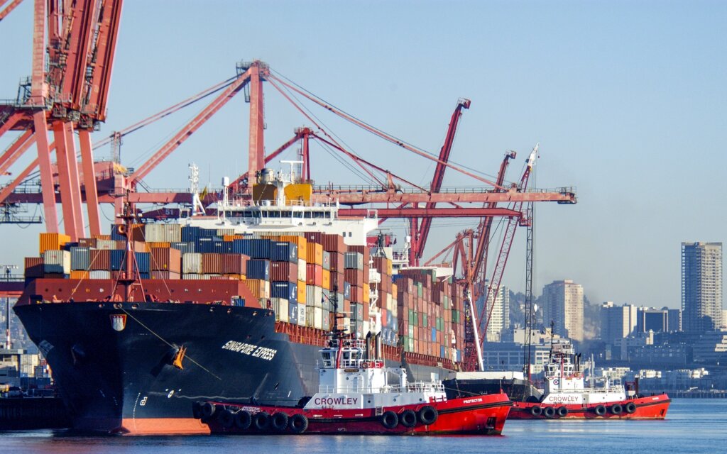Cargo ship loaded with shipping containers docked at a busy seaport.