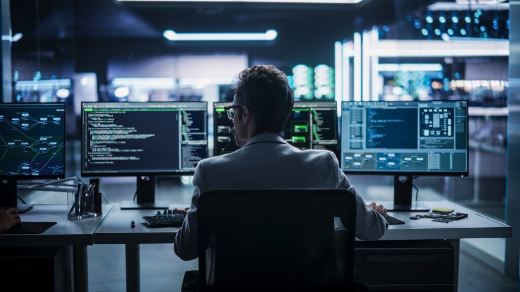 Security analyst monitoring AI and cybersecurity activity across multiple computer screens.