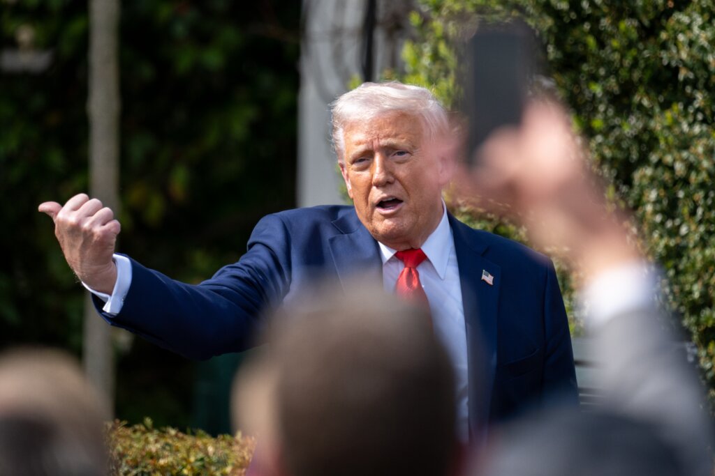 President Donald Trump gestures while speaking to reporters outdoors near the White House.