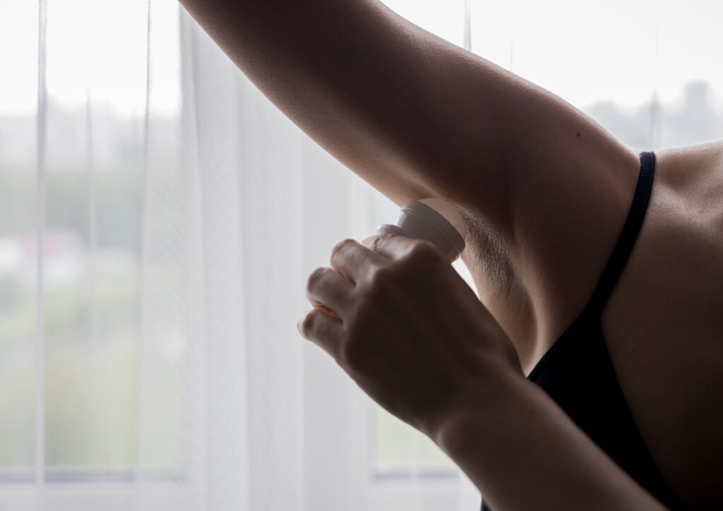 Person applying antiperspirant to an underarm to help control sweating.