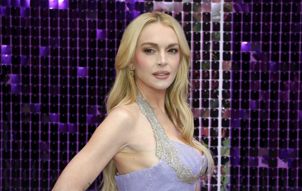 Lindsay Lohan looking to the side at a red carpet event, wearing a purple sequined halter dress.