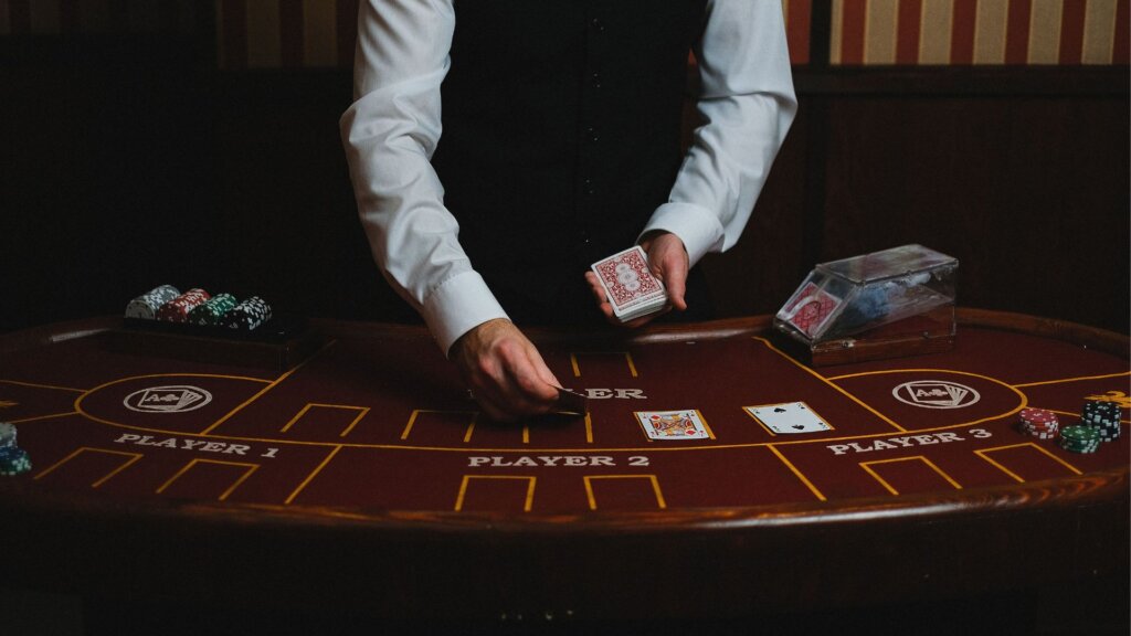 Casino dealer dealing playing cards at a table with poker chips.
