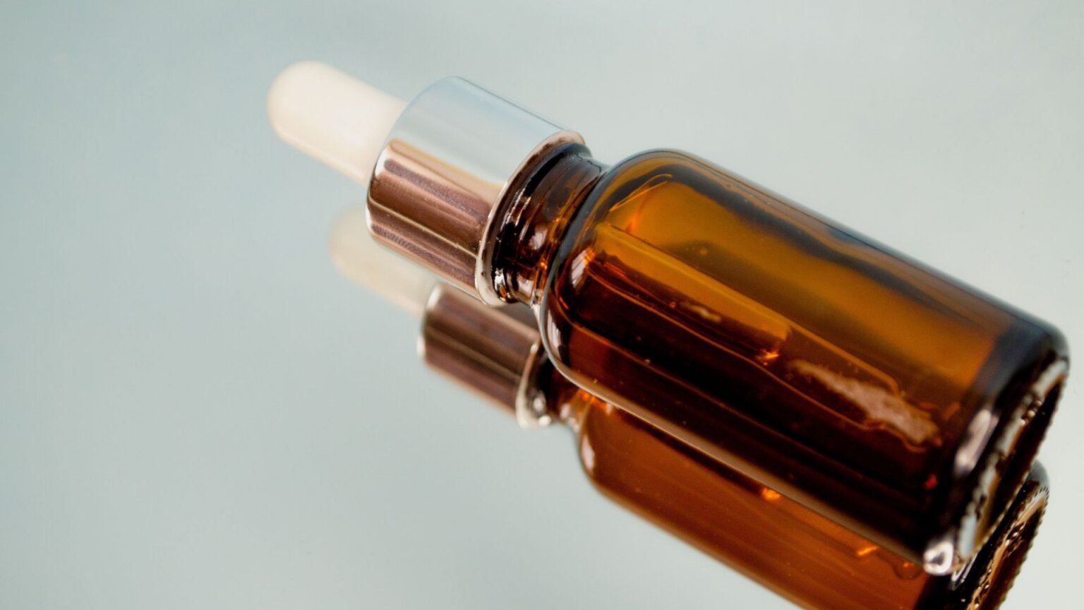 The Plant-Based Skincare Ingredient That’s Giving Retinol a Run for Its Money Amber glass skincare serum bottle with a dropper on a reflective surface.