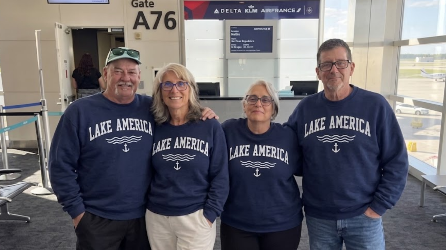A family in matching sweatshirts poses at an airport, capturing the lighthearted vacation moment that snowballed into a viral backlash and cost a Michigan credit union CEO her job.
