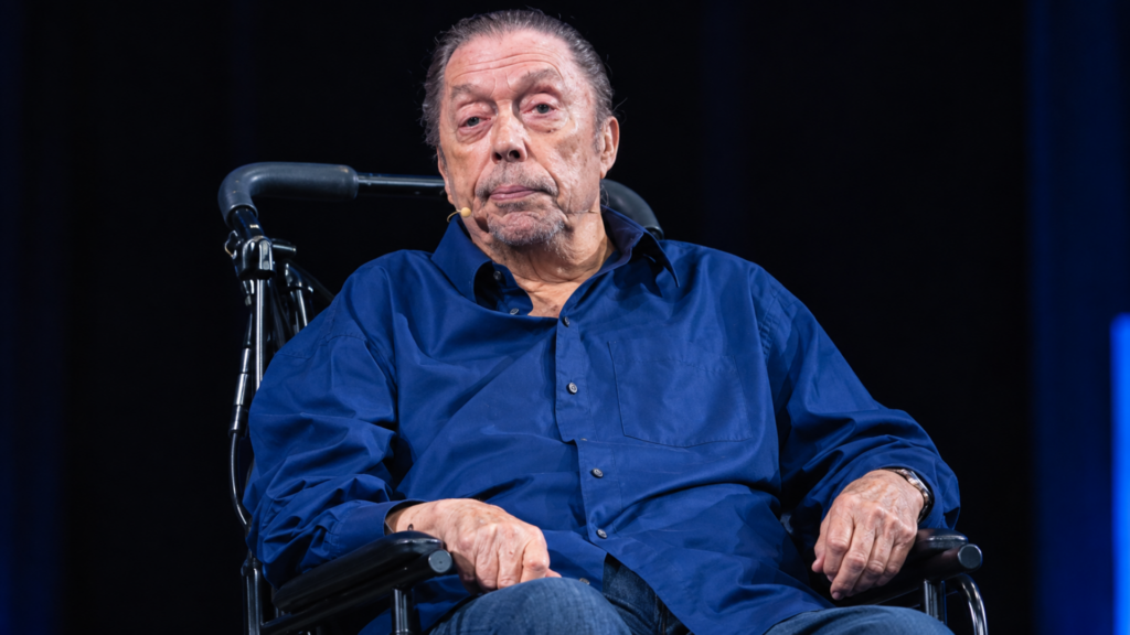 Actor Tim Curry wearing a blue button-down shirt sitting in a wheelchair.
