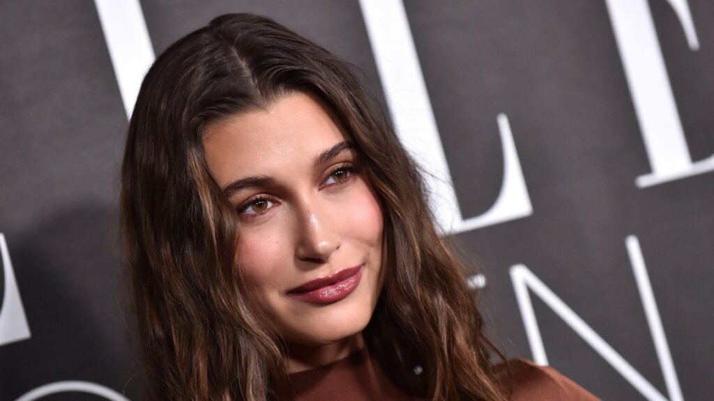 Hailey Bieber posing at an event backdrop.