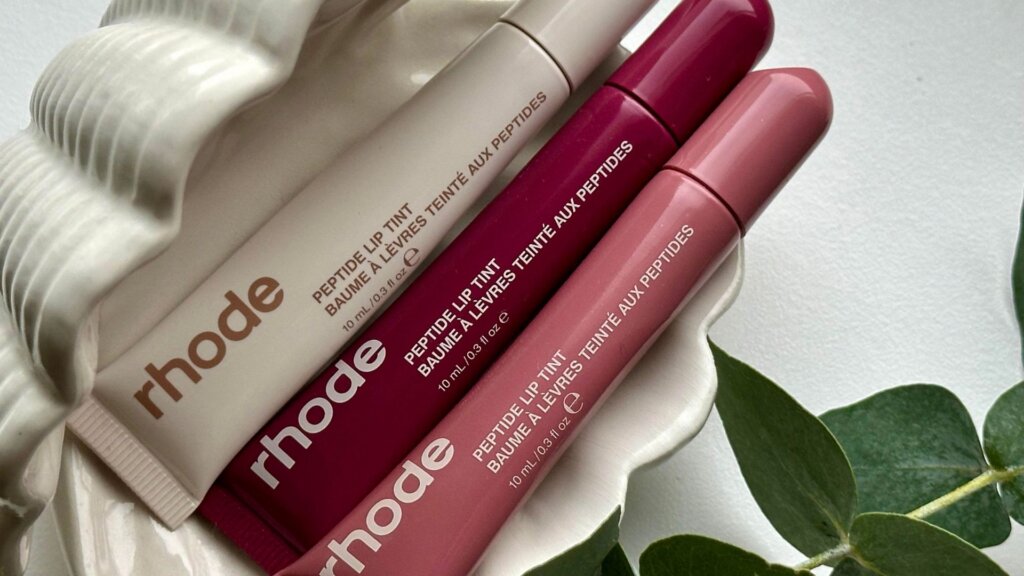 Three Rhode Peptide Lip Tint tubes in beige, berry, and pink shades.
