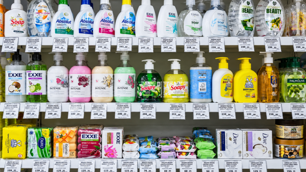 Supermarket shelves filled with various brands of liquid hand soaps and bar soaps.