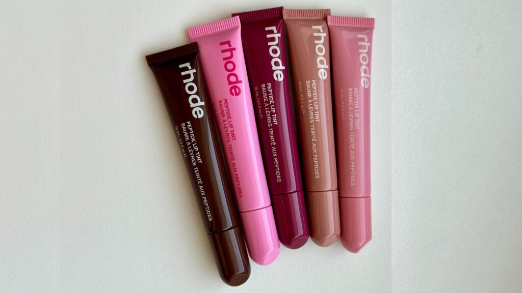 Five Rhode Peptide Lip Tint tubes arranged in brown, pink, berry, and neutral shades.