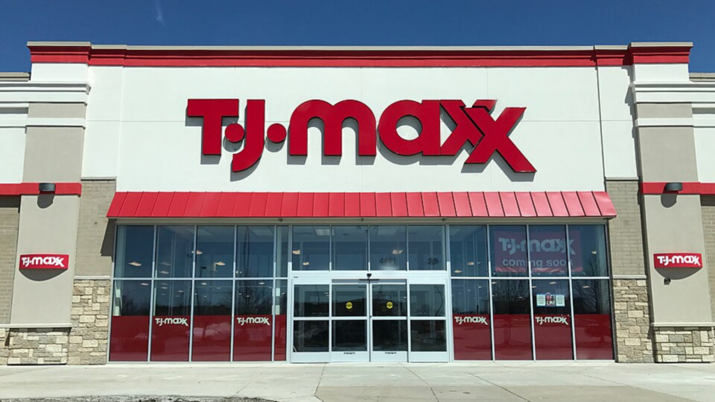 Exterior of a T.J. Maxx retail store with a large red logo sign above the glass entrance doors.