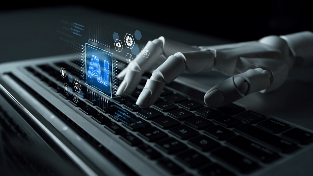 Robotic hand typing on a laptop keyboard with a glowing AI hologram hovering above it.
