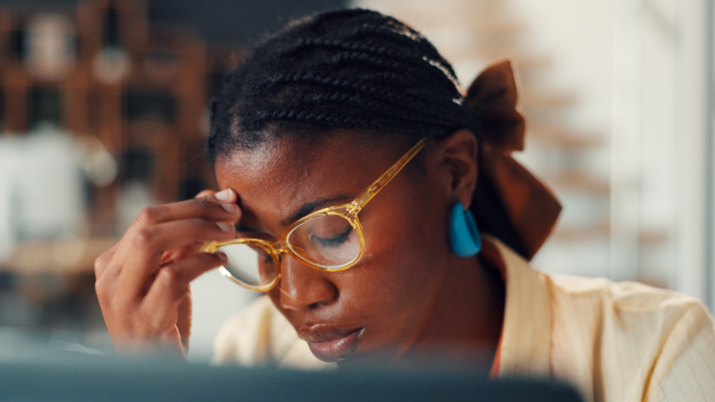 Close-up of a woman rubbing her forehead while looking down, seemingly stressed.