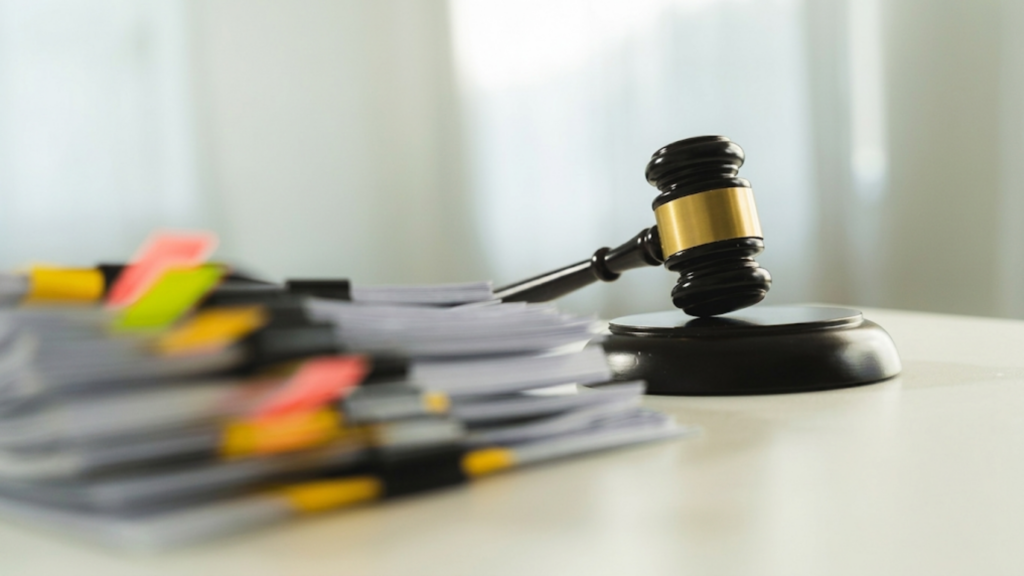 A judge's gavel rests on a desk surrounded by legal documents and papers, symbolizing the judicial process.