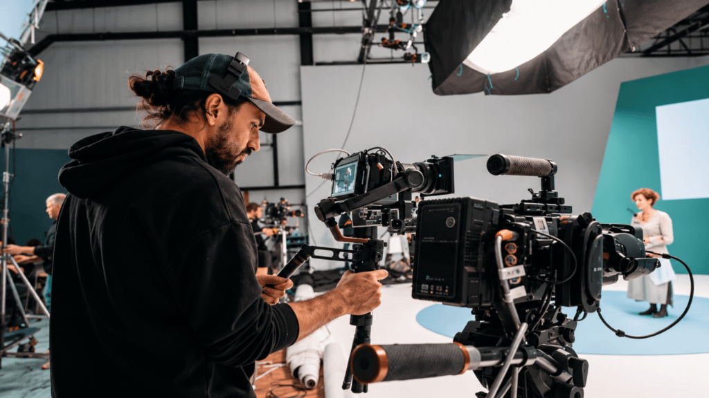 Cameraman operating a professional video camera rig on a studio film set.