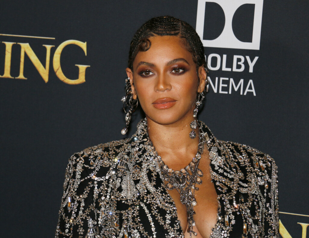 Beyoncé at a red-carpet event wearing a crystal-embellished black outfit, statement jewelry and a sleek braided hairstyle.