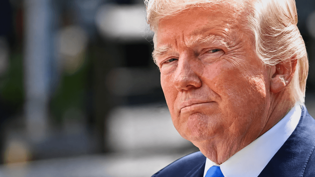 A close-up portrait of Donald Trump looking forward with a serious expression.