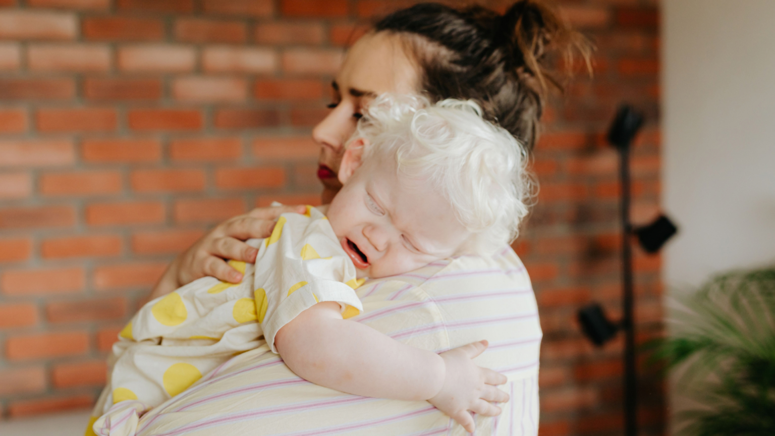 Keke Palmer Says There’s ‘A Lot of Elitism’ Around Parenting. Here’s What Bothers Her A mother gently holds her crying baby indoors, capturing a tender moment.