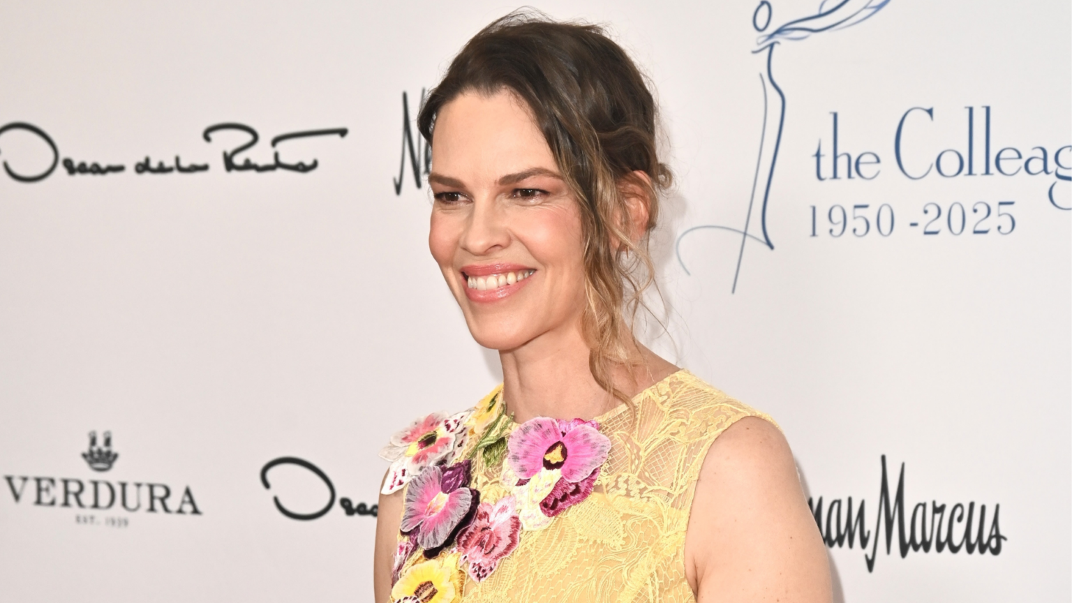 Hilary Swank Is Expecting Her Third Child at 52 and Has a Powerful Message for Parents Hilary Swank smiling in a yellow floral dress at a red carpet event.