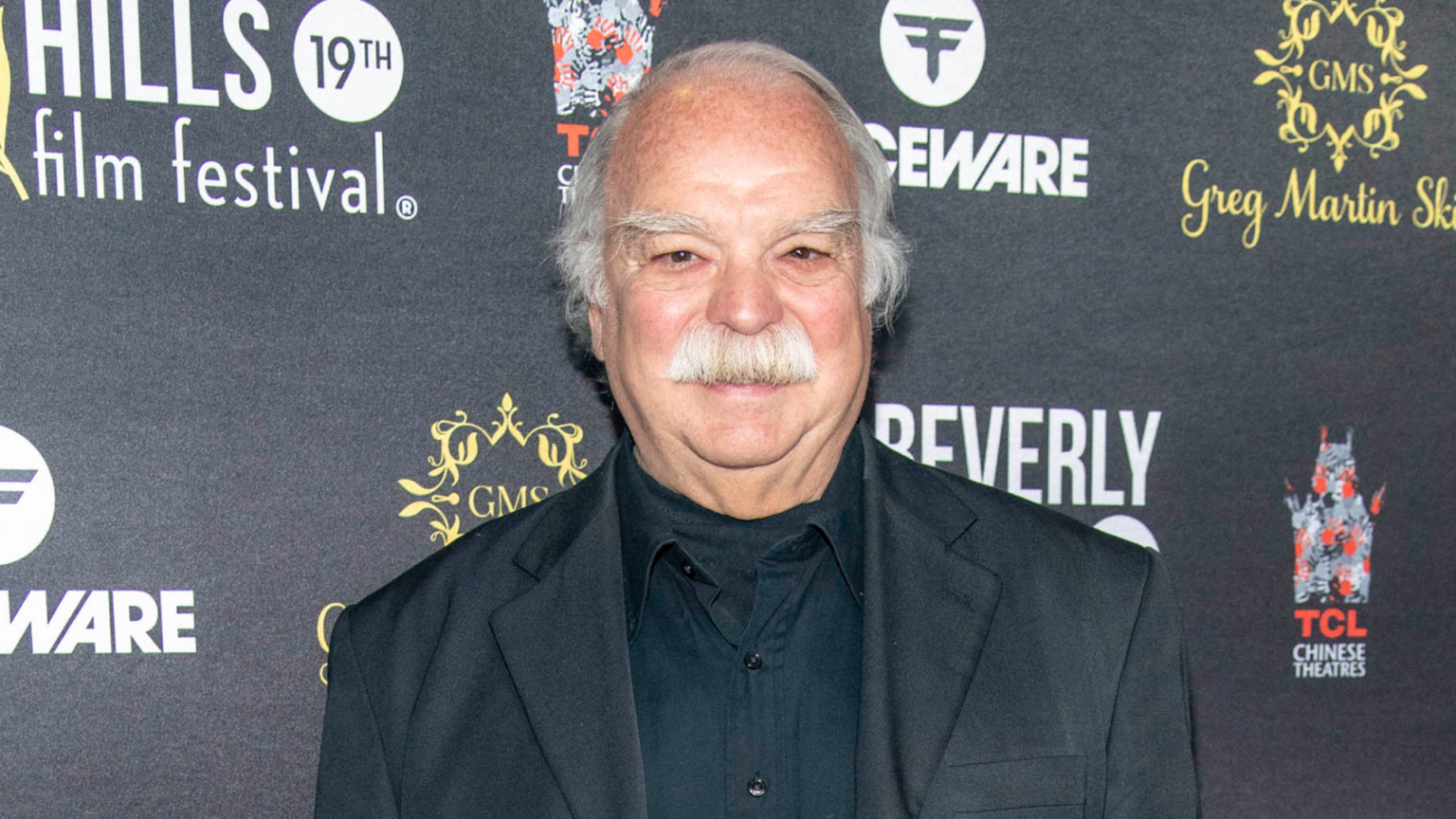 Actor Richard Riehle’s Cause of Death Revealed Weeks After His Passing Richard Riehle smiling on a red carpet with a film festival backdrop.