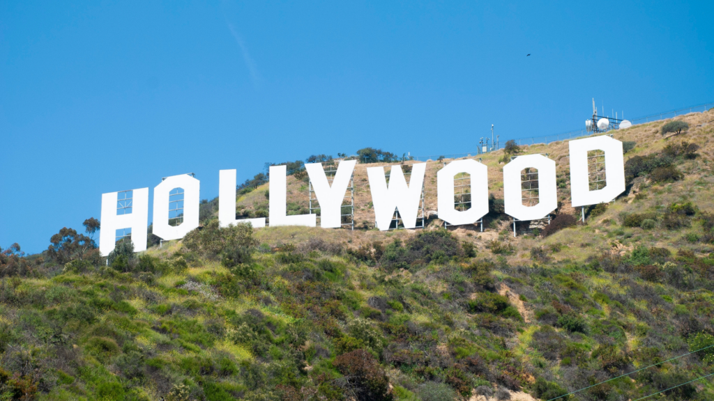 The Hollywood sign on a grassy hill under a clear blue sky.