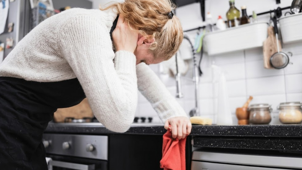 Woman with neck/head pain injury, tired from cleaning the house, kitchen and doing daily housework.