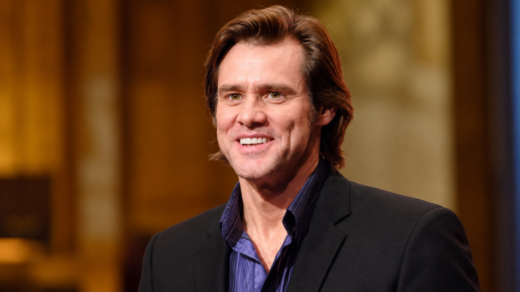 Jim Carrey smiling in a suit jacket and unbuttoned dress shirt.