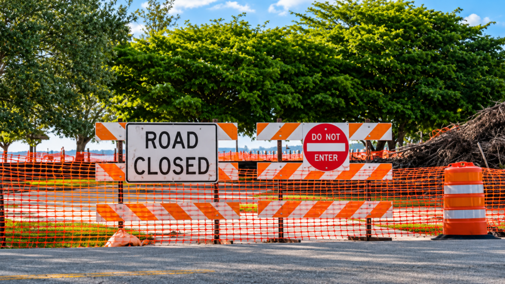 Orange barricades with "ROAD CLOSED" and "DO NOT ENTER" signs blocking access to a road.