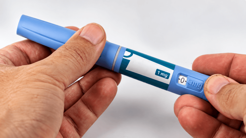 A close-up of a person holding a blue and white dose-injector pen labeled 1 mg.