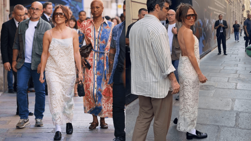 JLo in a white lace dress and sunglasses walks through a city street.