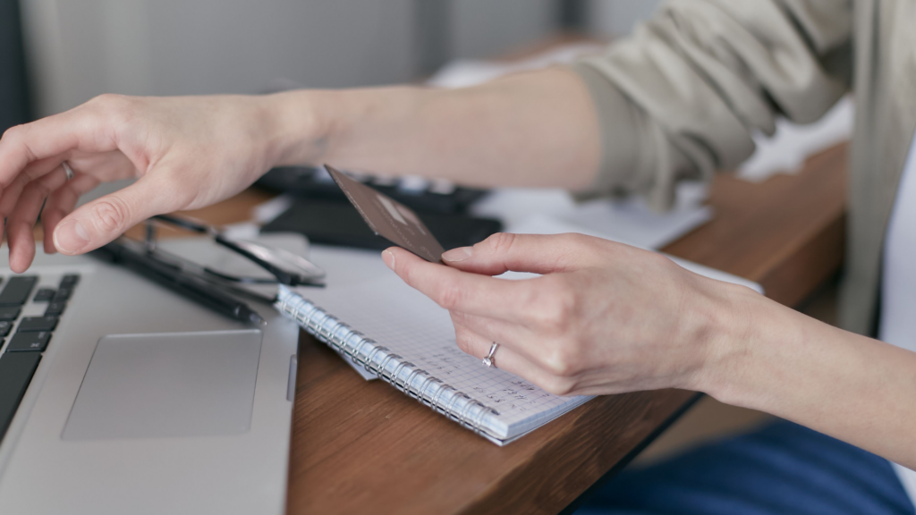 A person using a credit card on a laptop for online shopping or payment.