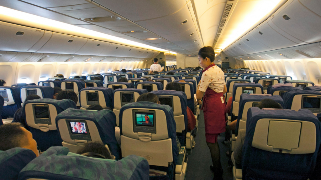 Flight attendant assisting passengers in a busy airplane cabin, ensuring a comfortable travel experience.