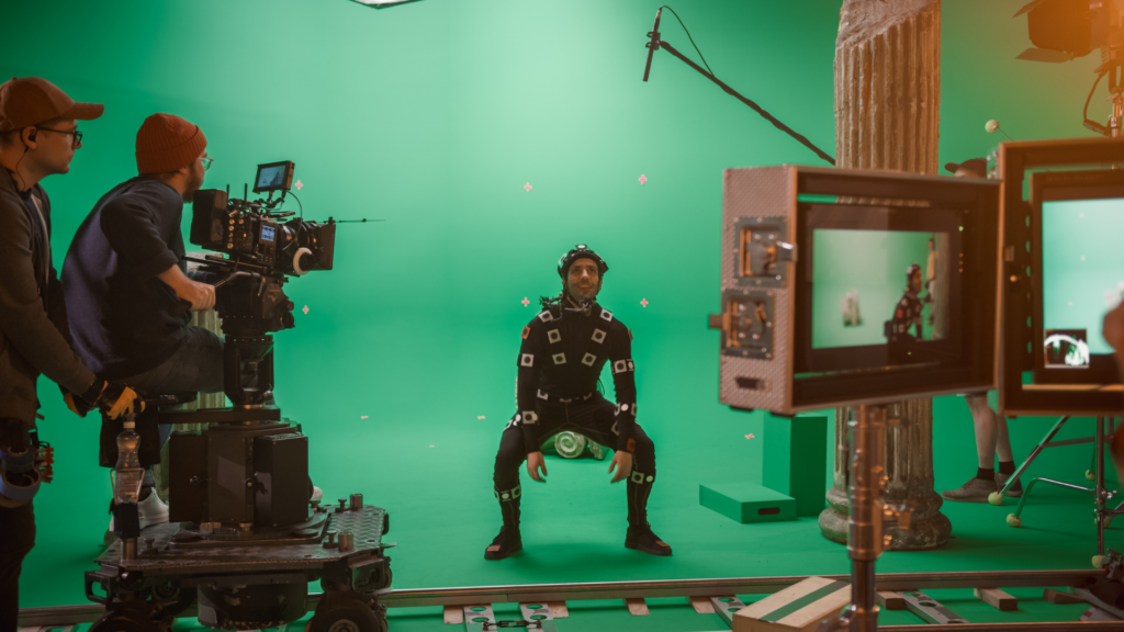 Actor in a motion-capture suit performing on a green screen stage.