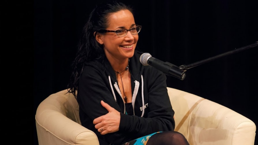 Janeane Garofalo seated in a chair, speaking into a microphone during a presentation or interview at Bumbershoot 2008.