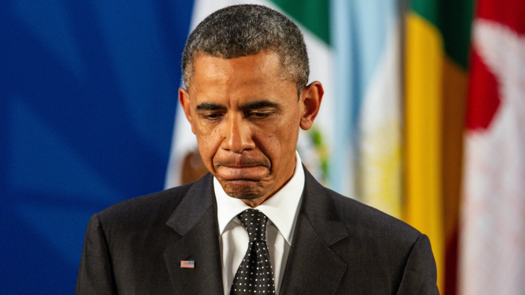 Former President Barack Obama looking down with a solemn expression.