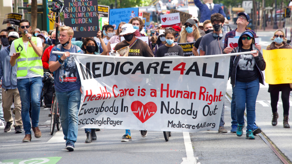 Protesters marching with a "Medicare 4 All" banner.