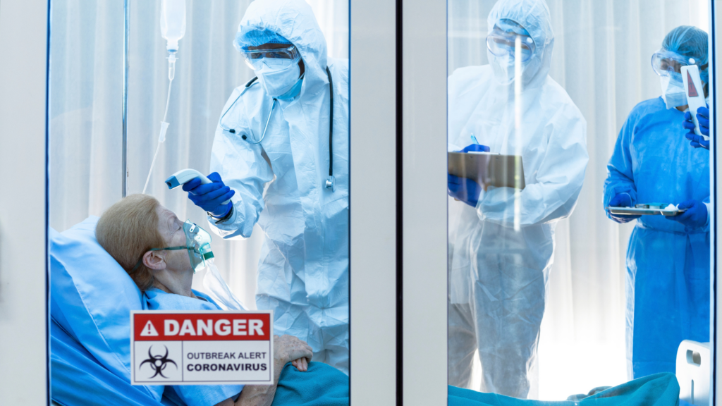 Healthcare workers in PPE treating a patient in a quarantine room.