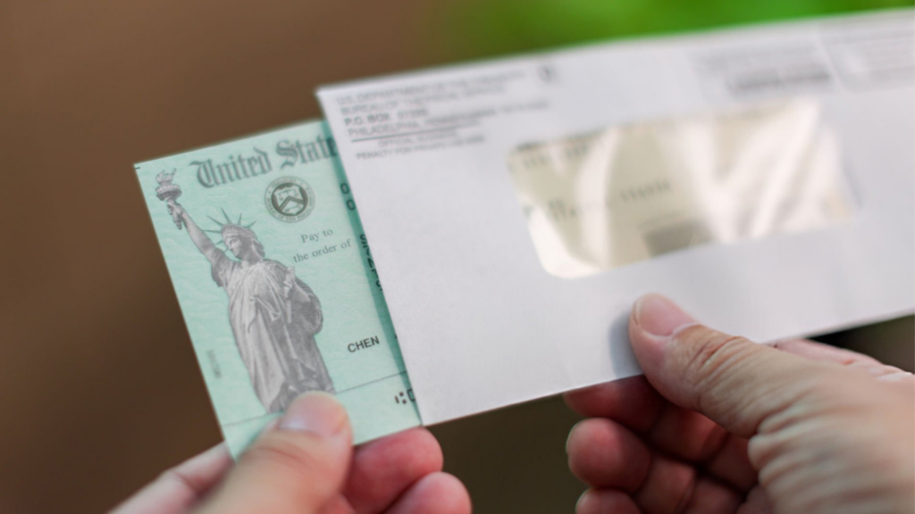 Hands pulling a United States Treasury check out of an envelope.
