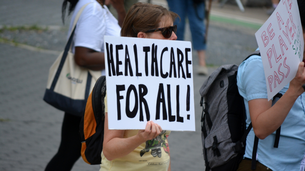 Protester holding a "Healthcare For All!" sign.