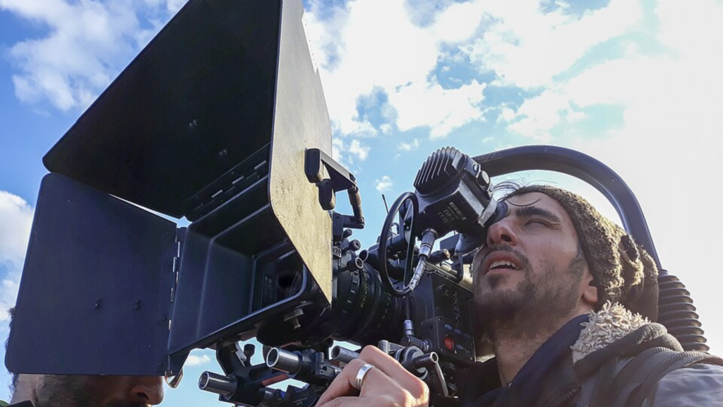 Close-up of a camera operator looking through a professional cinema camera viewfinder.