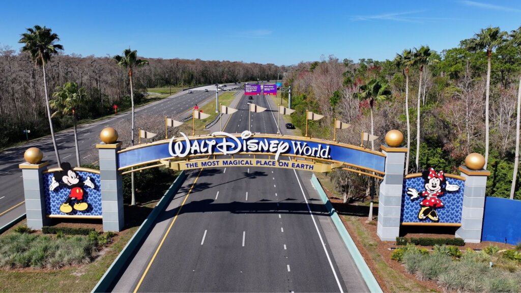 Aerial view of the Walt Disney World entrance arch with Mickey and Minnie Mouse figures over an empty highway.