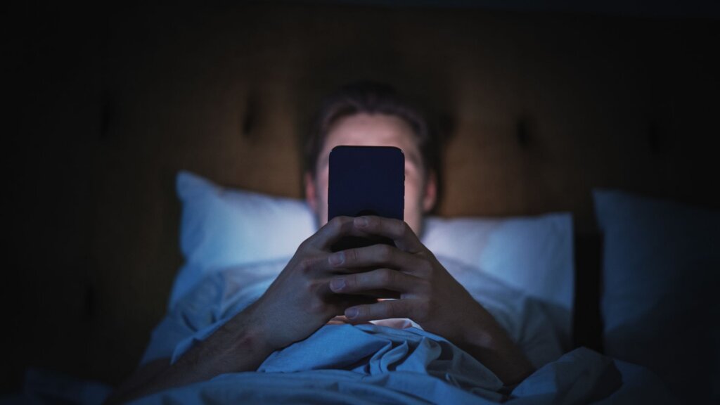 Person in bed looking at phone in the dark.