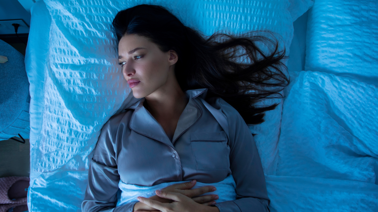 woman lying on back, awake in bed at night, having insomnia.