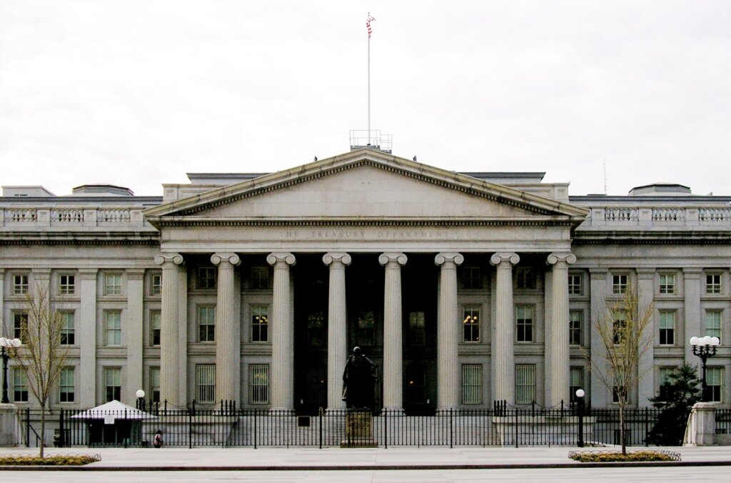 Front view of the U.S. Treasury Department building in Washington, D.C., with its columns and American flag.