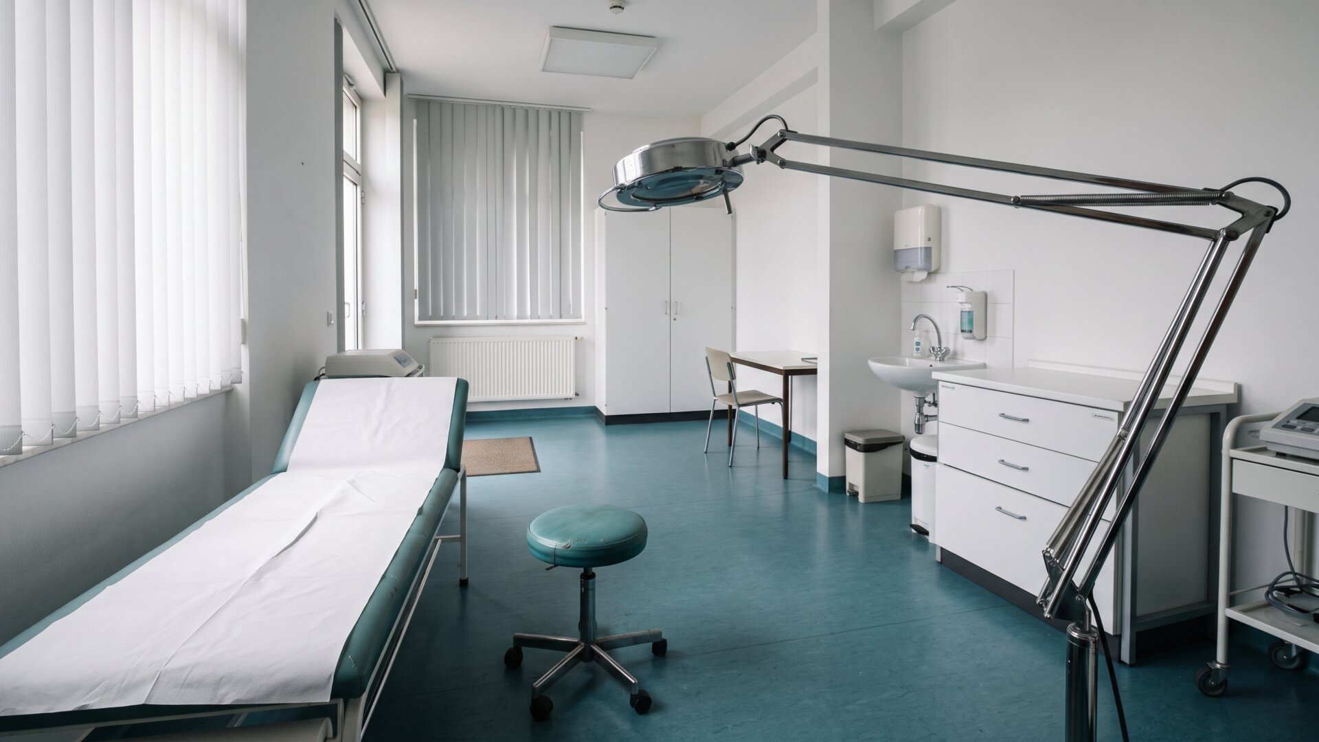 A clinical examination lamp and stool in an empty consulting room, the setting where the study's more severe outlier cases would be assessed.