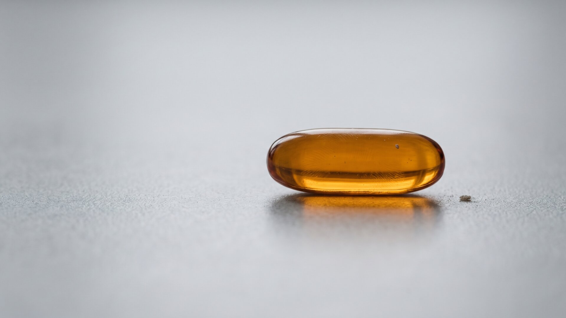 A single amber softgel capsule isolated on a plain surface, standing in for the supplement at the center of the story without naming or branding it.