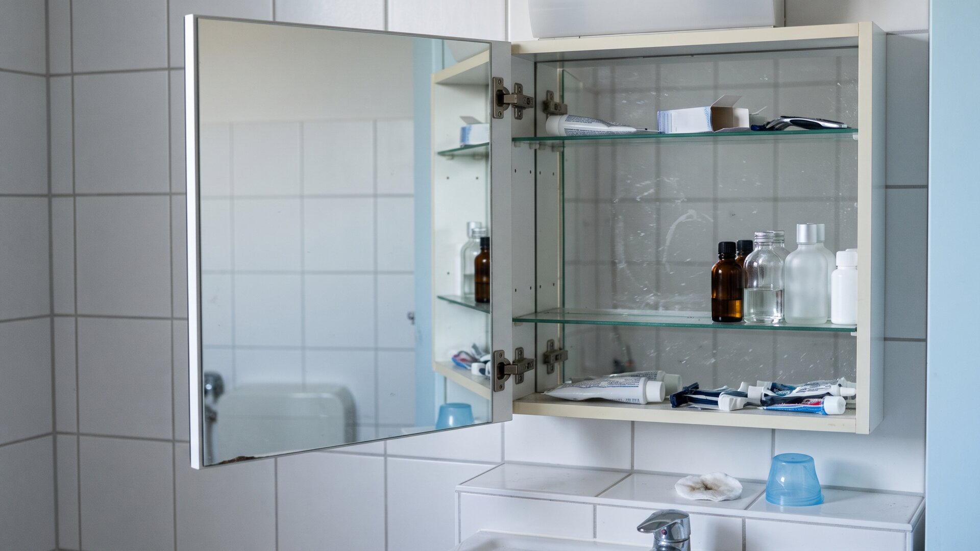 A bathroom mirror cabinet open with one shelf half emptied, standing for the reactions that sent patients back to reassess what they had been applying.