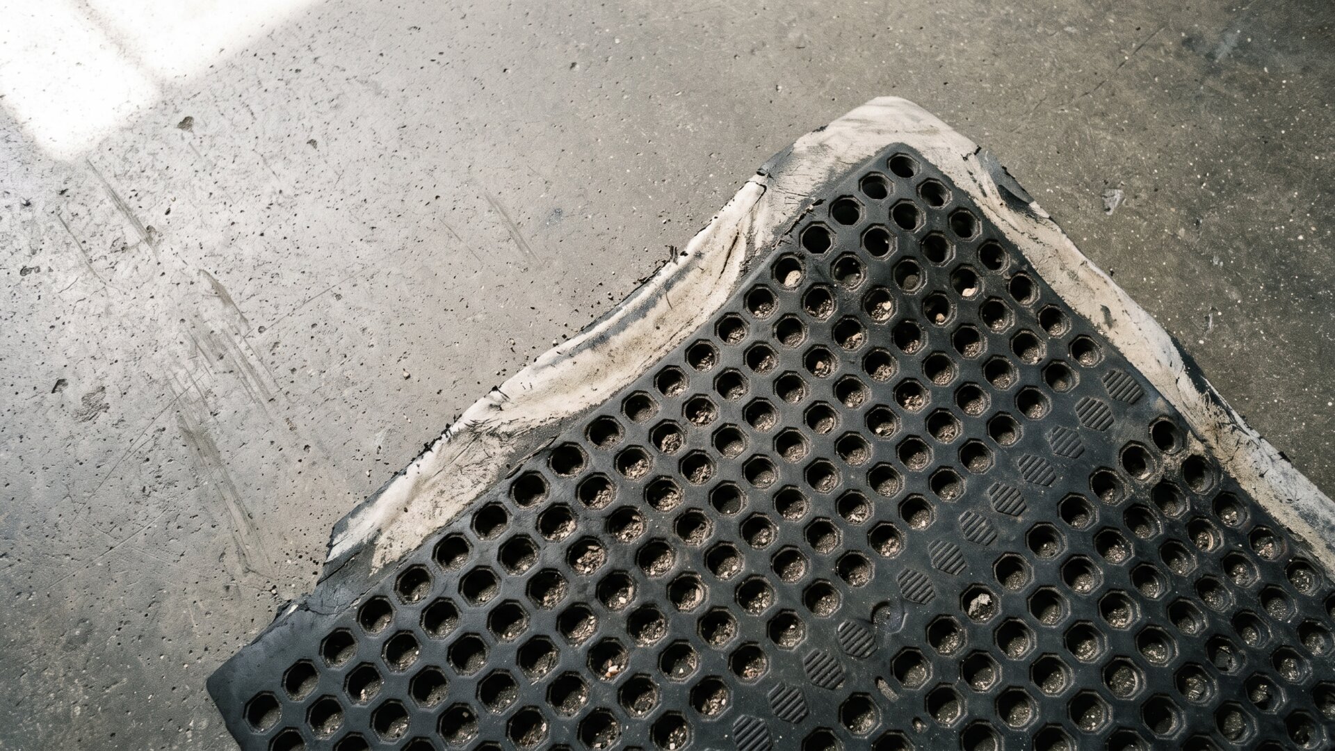 A worn rubber anti-fatigue mat on hard flooring, the specific intervention named in slide 4's discussion of standing work research.