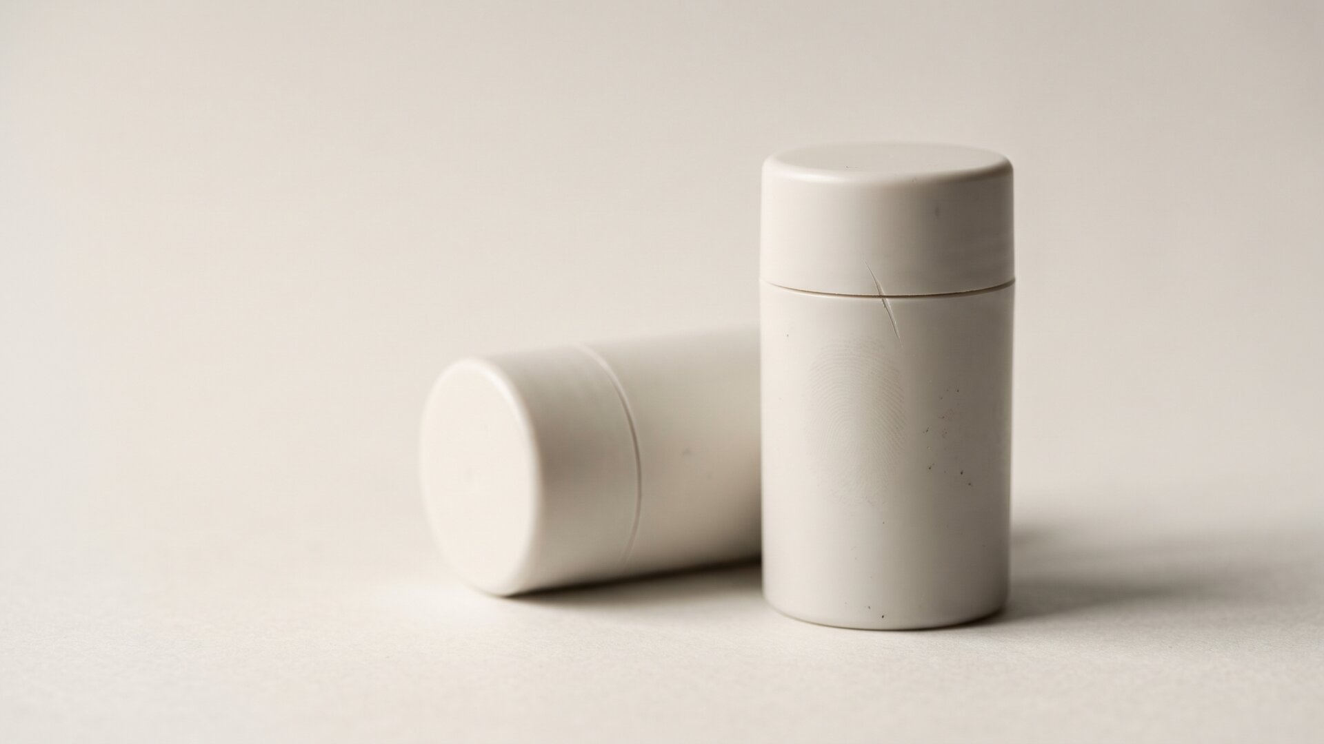 A macro frame of a plain cylindrical container on seamless paper, showing the minimal packaging language slide 8 says is easy to reproduce.